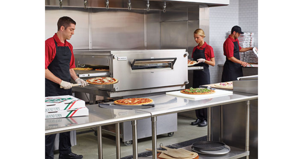 Młodzi ludzie pracujący w kuchni w restauracji przy pieczeniu pizzy